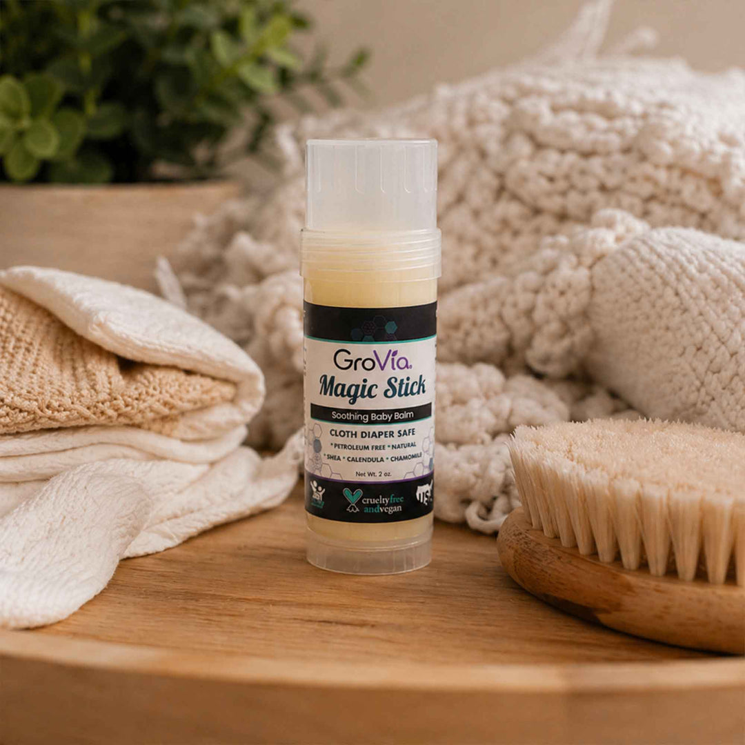 GroVia Magic Stick on a wooden surface with towels and a brush in the background