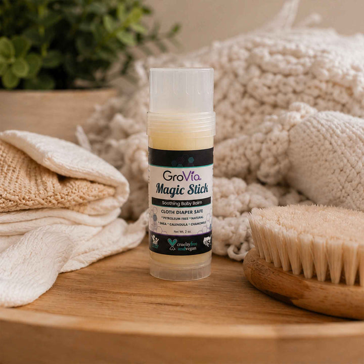 GroVia Magic Stick on a wooden surface with towels and a brush in the background
